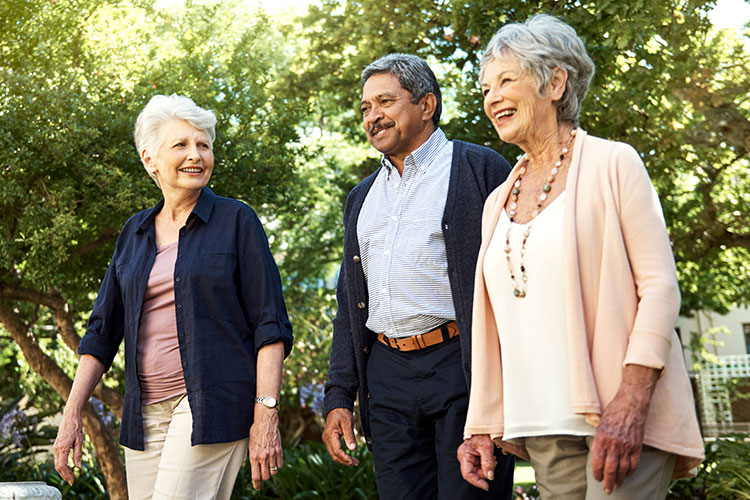 Two older women and an older man enjoying a walk outside