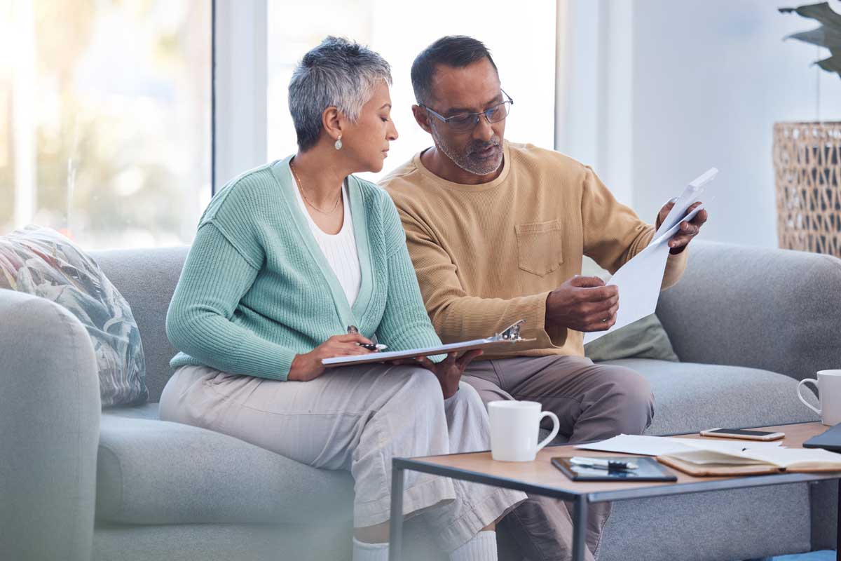couple-sitting-on-couch-reviewing-documents couple sitting on couch reviewing documents